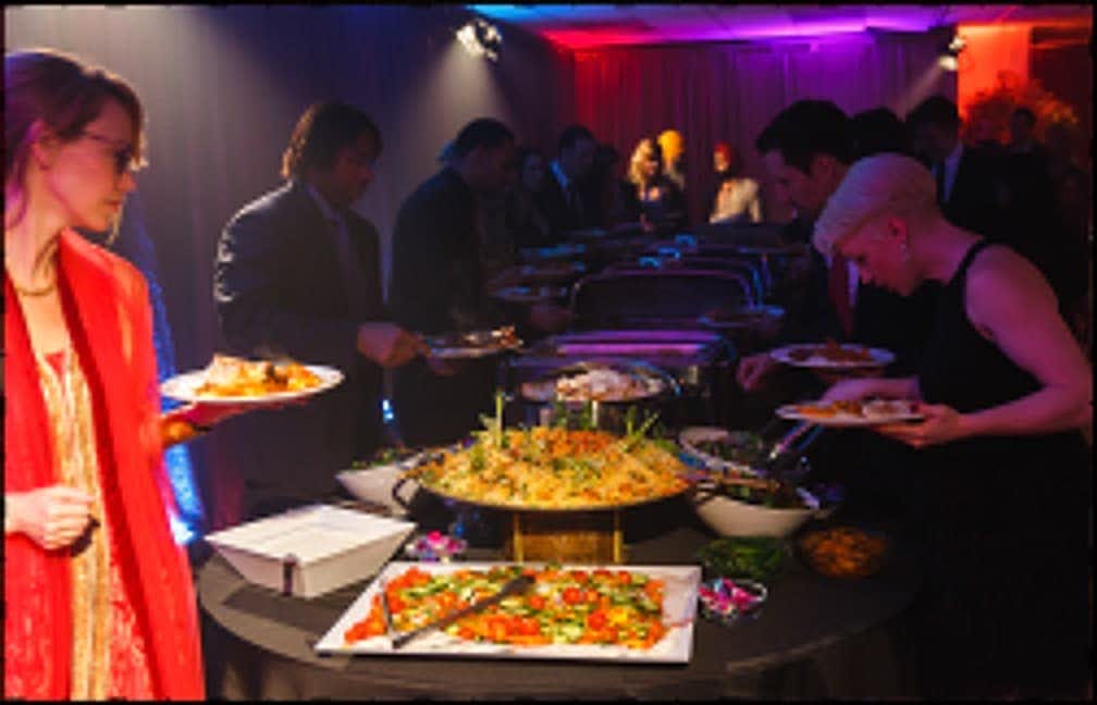 Indian buffet line at a wedding with trays of curries and rice